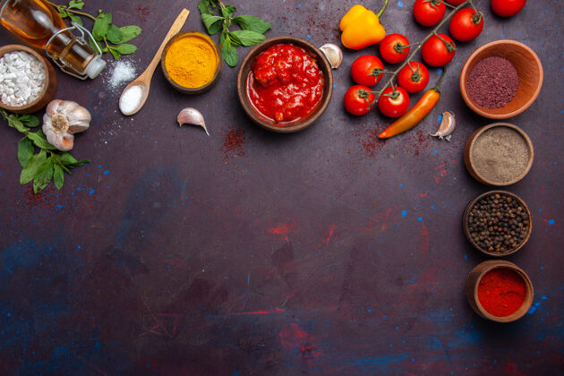 胡椒顶视图不同的调味品与新鲜西红柿在黑暗的空间配料生的水果