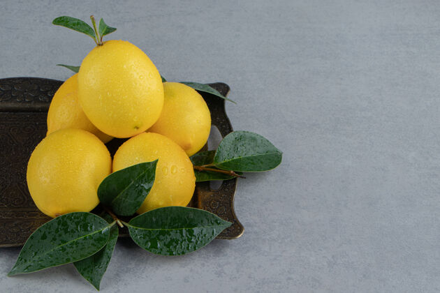 配料一小堆柠檬和树叶放在大理石上的华丽托盘上饮食美味有机
