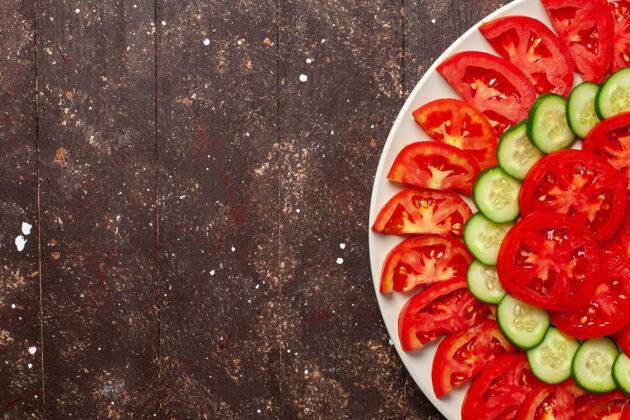 晚餐在棕色的桌子上俯瞰新鲜的红色西红柿切片黄瓜新鲜沙拉蔬菜西瓜菜肴