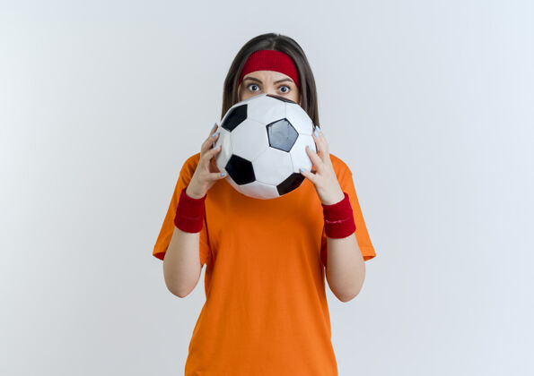 女子令人印象深刻的年轻运动女子戴着头带和手腕举行足球从后面看它孤立人腕带印象