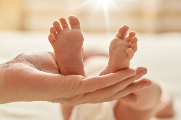 医疗妈妈的手抱着刚出生的宝宝的赤脚 妈妈为宝宝做按摩 让宝宝的神经系统正常化 动作协调发展腿无脸皮肤