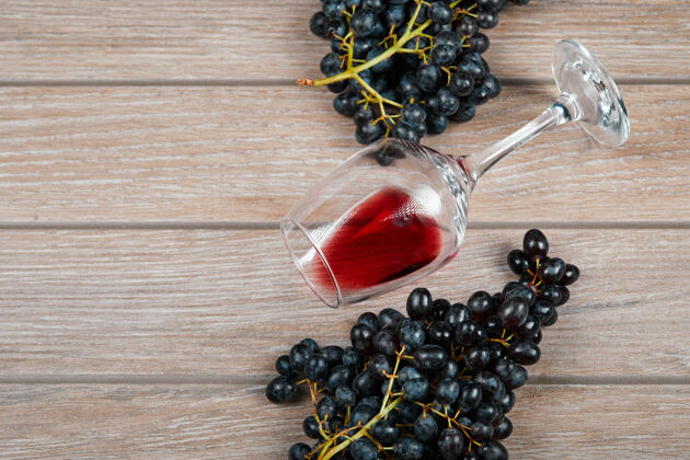 葡萄酒一束黑葡萄和一杯葡萄酒在木制背景上高质量的照片自然桌子优雅