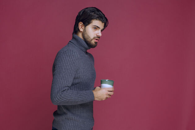 休息一个穿着灰色毛衣的男人手里拿着一个咖啡杯工人人服装