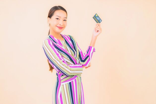 银行用智能手机和彩色信用卡描绘美丽的亚洲年轻女子购物女士年轻