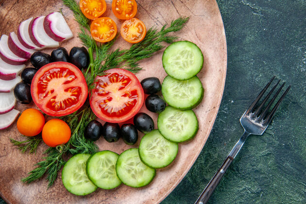 盘子近距离观看新鲜切碎的蔬菜橄榄在棕色盘子和叉子上的绿黑色混合色背景水果切碎的蔬菜食物