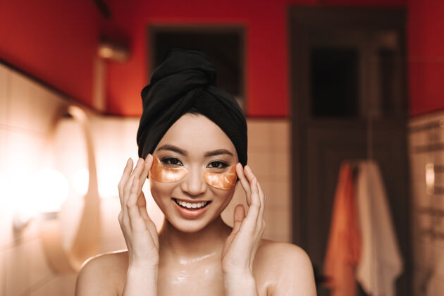 面部头上裹着毛巾的亚洲女人做面部按摩房子身体护理眼罩