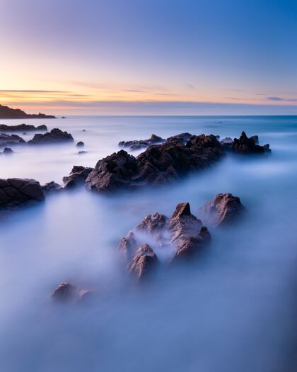 海洋日落时格恩西岛海景的垂直长曝光镜头岩石海岸地平线