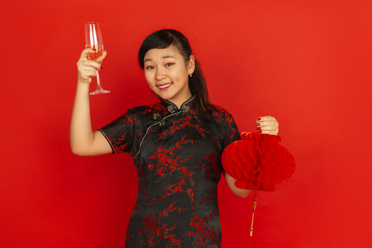 照明喝香槟 捧着灯笼2020年中国新年快乐红色背景上的亚洲少女肖像穿着传统服装的女模特看起来很快乐庆祝 情感复制空间传统年愿望