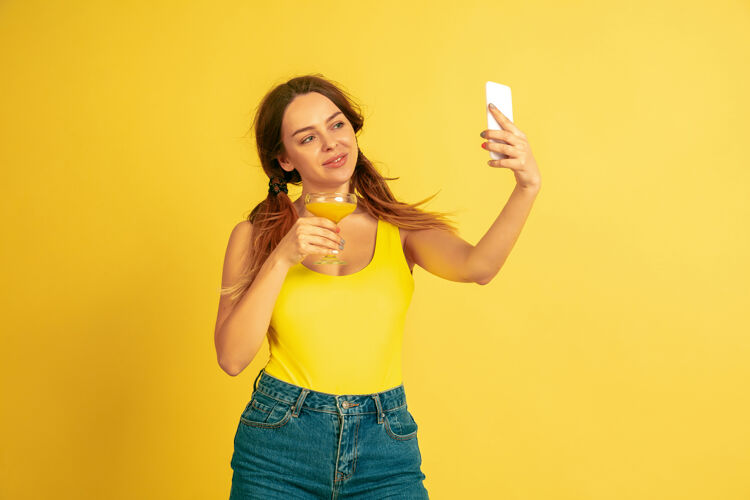 情感自拍 视频博客 微笑黄色工作室背景上的白人女性肖像美丽的女性模特人类情感的概念 面部表情 销售 广告夏季 旅游 度假行政公司面部