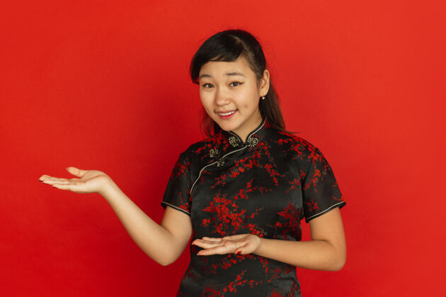 服装做手势 邀请客人2020年中国新年快乐红色背景上的亚洲少女肖像穿着传统服装的女模特看起来很快乐庆祝 人类情感复制空间普通话美丽年轻