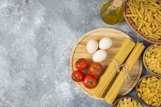 俯视图各种生面食 鸡蛋 新鲜西红柿和大理石表面的一瓶油碗干的晚餐