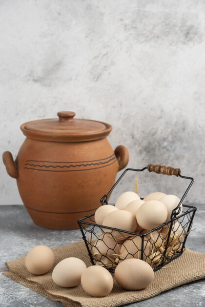 鸡蛋金属篮生鸡蛋和古董花瓶在大理石表面柳条有机膳食