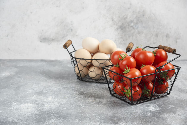 成熟的柳条篮子的生有机鸡蛋和红色西红柿放在大理石上烹饪菜肴农场