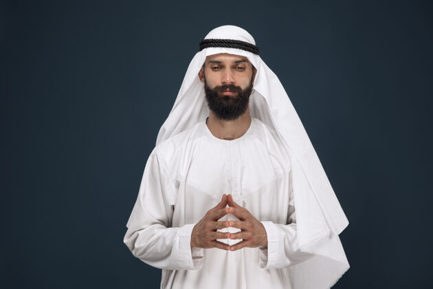 震惊深蓝色工作室背景上的半身阿拉伯沙特商人肖像年轻的男模祈祷着 看上去很体贴商业 金融 面部表情 人类情感的概念表情年轻文化