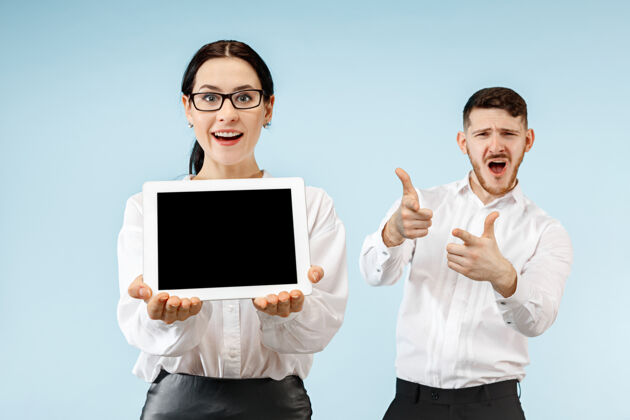 伙伴在蓝色工作室背景上 惊讶的商务男女微笑着 展示着笔记本电脑或平板电脑的空屏幕微笑情感女性