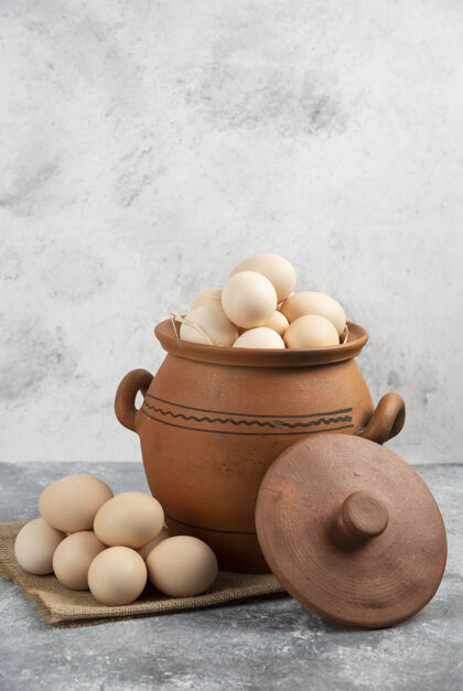 天然装满生鸡蛋的泥锅放在大理石上有机食品生的