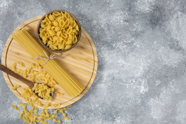顶视图一碗碗生的干意大利面和放在大理石表面的意大利面意大利面烹饪烹饪