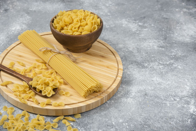 烹饪一碗碗生的干意大利面和放在大理石表面的意大利面晚餐通心粉烹饪