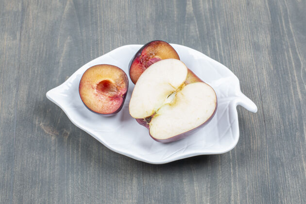 新鲜把红苹果片和李子片放在一个白色盘子里美味李子食物