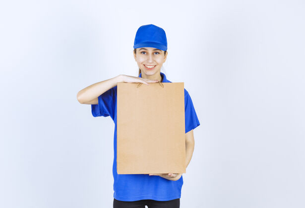 安全穿着蓝色制服的女孩手里拿着一个纸板购物袋快递邮件工人