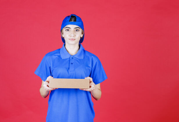 人类穿着蓝色制服的女信使手里拿着一个纸板箱订单人食物