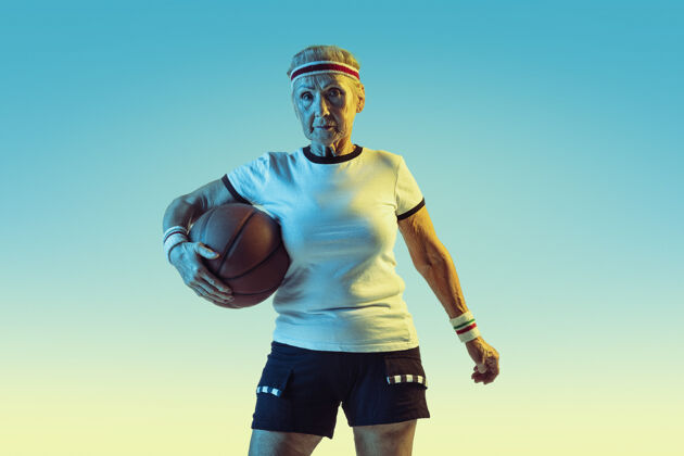 业余运动装的高级女性在渐变背景下打篮球 霓虹灯身材匀称的女性模特保持活跃运动 活动 运动 健康 自信的概念复制空间爱好设备女性