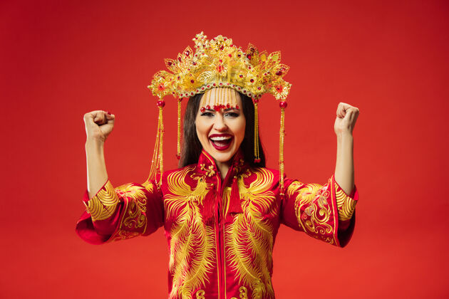 传统中国传统的优雅女子在摄影棚的红色背景美丽的女孩穿着民族服装中国新年 优雅 优雅 表演者 表演 舞蹈 女演员 服装的概念成人民族文化