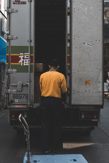 东京穿黄色毛衣的男人在灰色卡车后面人货车车辆