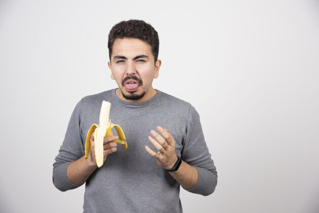 人一个年轻人厌恶地吃香蕉指点肖像年轻