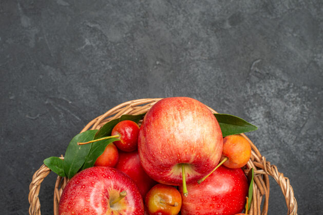 特写顶部特写镜头：深色桌子上篮子里的水果苹果和樱桃美味樱桃餐桌