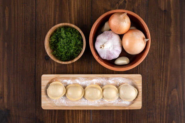蔬菜一块木板 上面放着自制的佩尔曼饺子和一碗洋葱洋葱饺子自制的