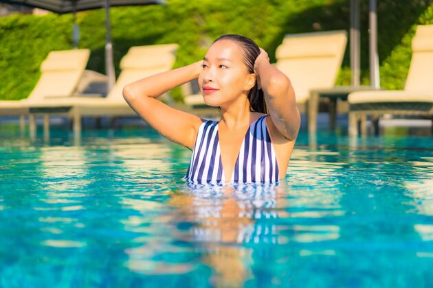 阳光肖像美丽的年轻女子放松微笑休闲度假酒店游泳池周围度假村成人女士