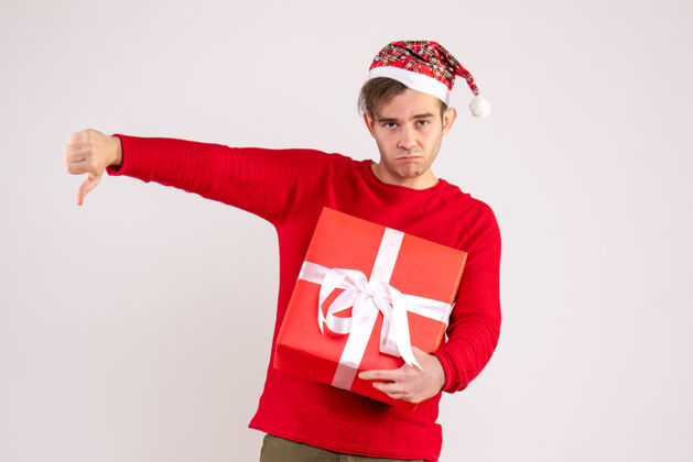 微笑前视图：戴圣诞帽的年轻人在白色背景上做拇指朝下的手势帽子圣诞节使
