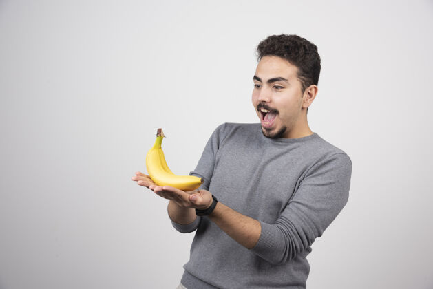 肖像年轻人看着灰色的香蕉欢呼自然成人