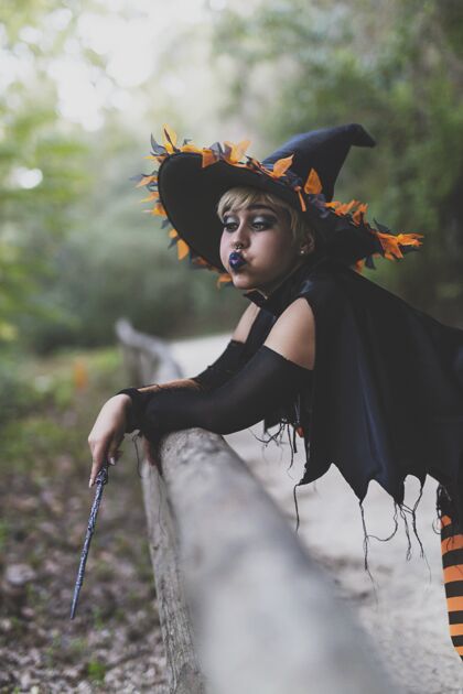 服装一个女人穿着女巫的化妆和服装 手持魔杖 在森林里拍摄的垂直镜头神秘垂直时尚