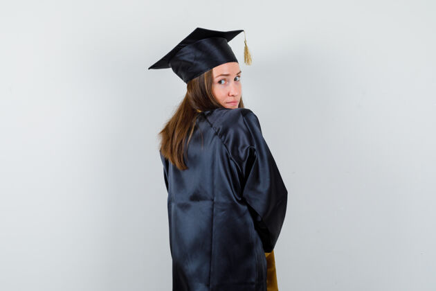 肩膀穿着学院服的女毕业生看着肩上的相机 看起来很可爱 背影欢呼单身多样性
