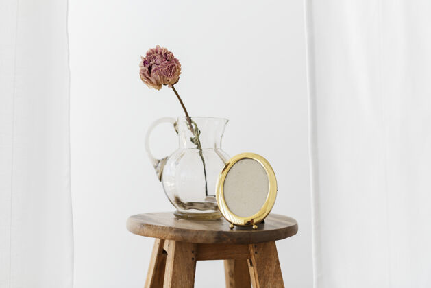牡丹在一间白色的房间里 把牡丹花放在木凳上的玻璃罐里晾干叶木椅窗帘