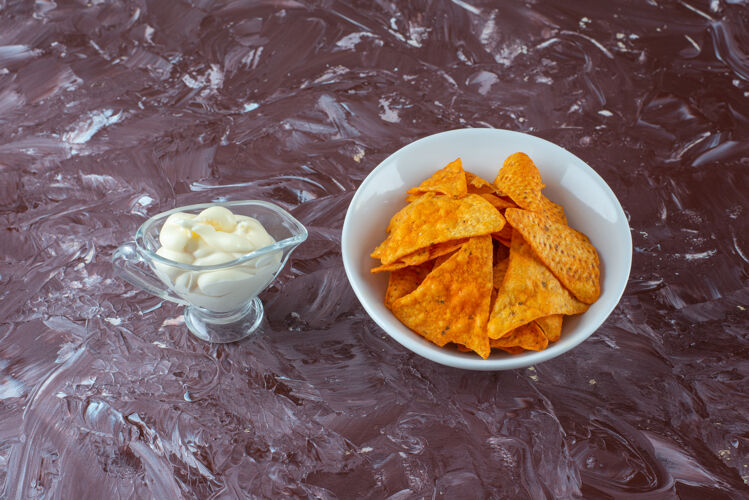 薯条一碗辛辣的薯片和一杯酸奶放在大理石表面美味快餐香料