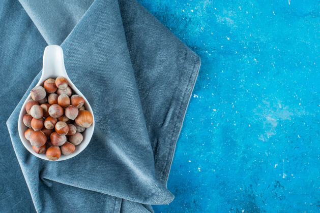 美味把榛子放在勺子里 放在蓝色表面的一块布上美味榛子大自然