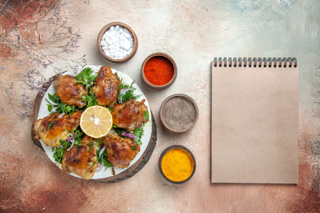 盘子奶油笔记本旁边的碗里放着柠檬香草香料的鸡肉俯视图午餐顶部蔬菜