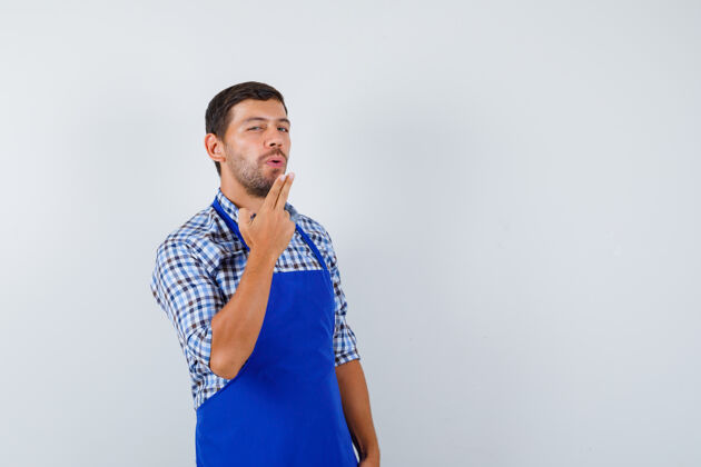 烹饪穿着蓝色围裙和衬衫的年轻男厨师成人围裙厨师