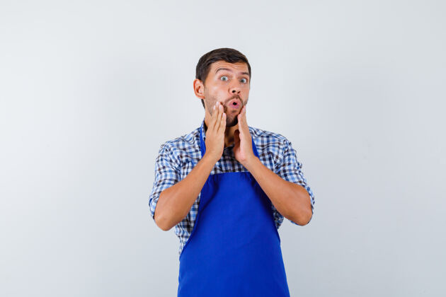 烹饪穿着蓝色围裙和衬衫的年轻男厨师男士厨师帅哥