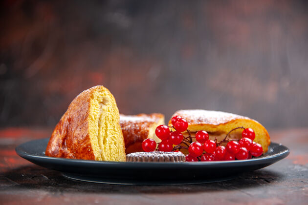 浆果前视图美味的切片派与红色浆果在黑暗的桌子上蛋糕可食用水果前