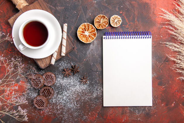 早晨俯瞰一杯茶 配上饼干和记事本 在黑暗的餐桌上举行饼干黑暗仪式早餐浓缩咖啡热的