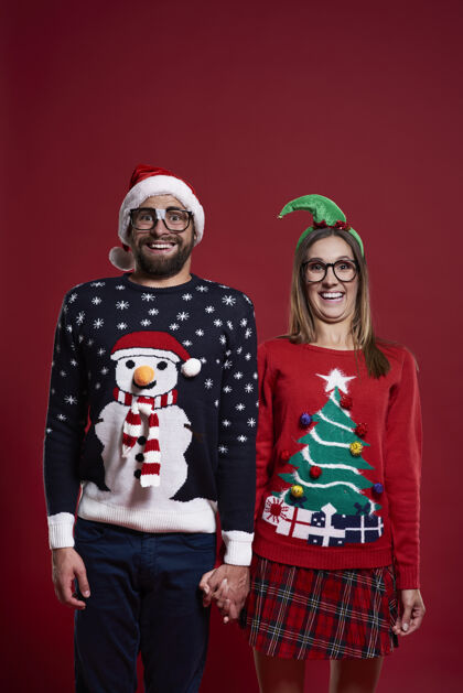 微笑一对穿着圣诞服装的夫妇的肖像调情女人乐趣
