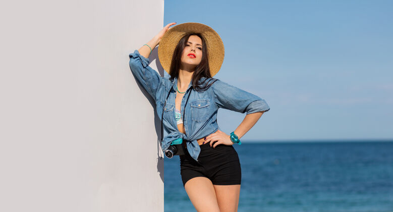沙滩穿着短裤戴着草帽在沙滩上摆姿势的漂亮女人阳光太阳热带