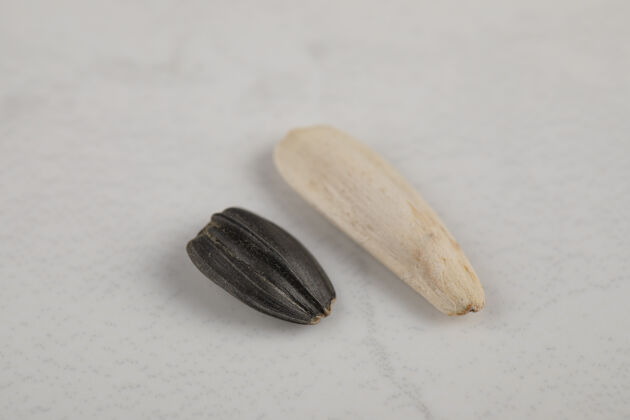熟的白色和黑色的向日葵黑色的种子放在白色的表面贝壳堆仁
