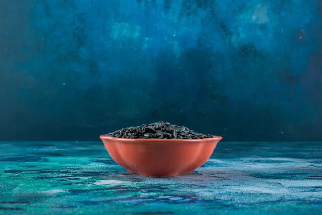 可口把葵花籽放在大理石表面的碗里碗果仁美味