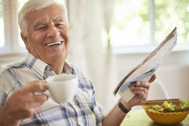 老年早上喝咖啡和看报纸是一种很好的放松衰老的过程坐着阅读