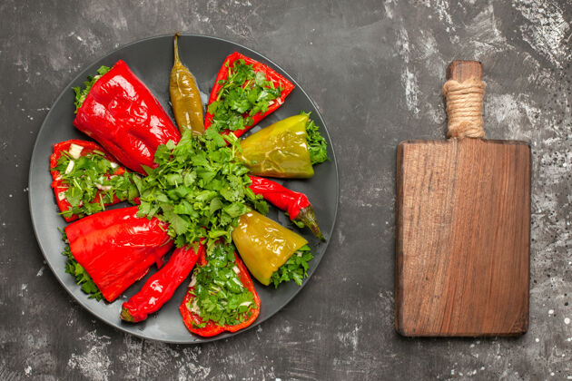 胡椒顶部特写视图五颜六色的胡椒盘与草药旁边的切菜板切割沙拉盘子